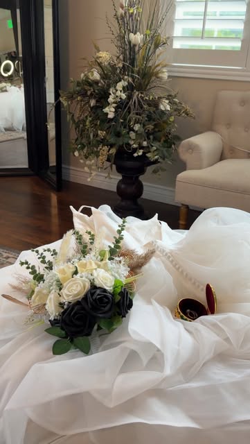 A bridal bouquet and rings on flowing white fabric